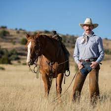 2 cowboys Morgan and Jhon wearing brown poncho and leather gloves grabs each one end tight, and they waving a large bedsheet up and down endless times on their hands In the nightly desert on a strong wind.